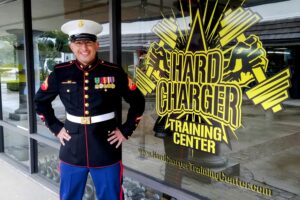 Marine Miguel in his Dress Blues Uniform standing in front of Hard Charger Training Center his Gym in Thousand Oaks, CA